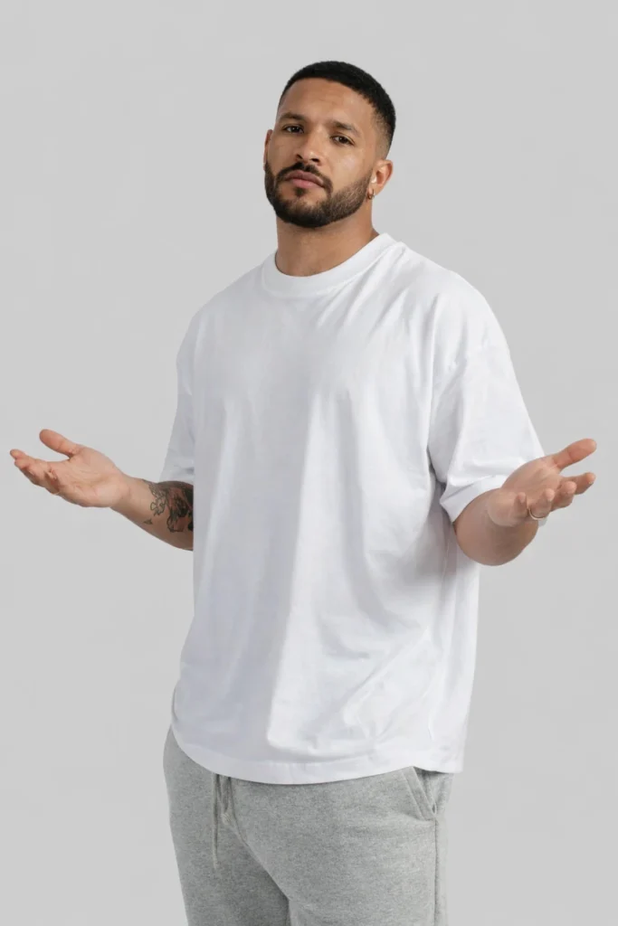 A clean studio image of a man wearing a white oversized T-shirt paired with neutral sweatpants. The relaxed silhouette, soft fabric, and minimal styling highlight a versatile everyday essential suitable for casual wear and modern streetwear collections.