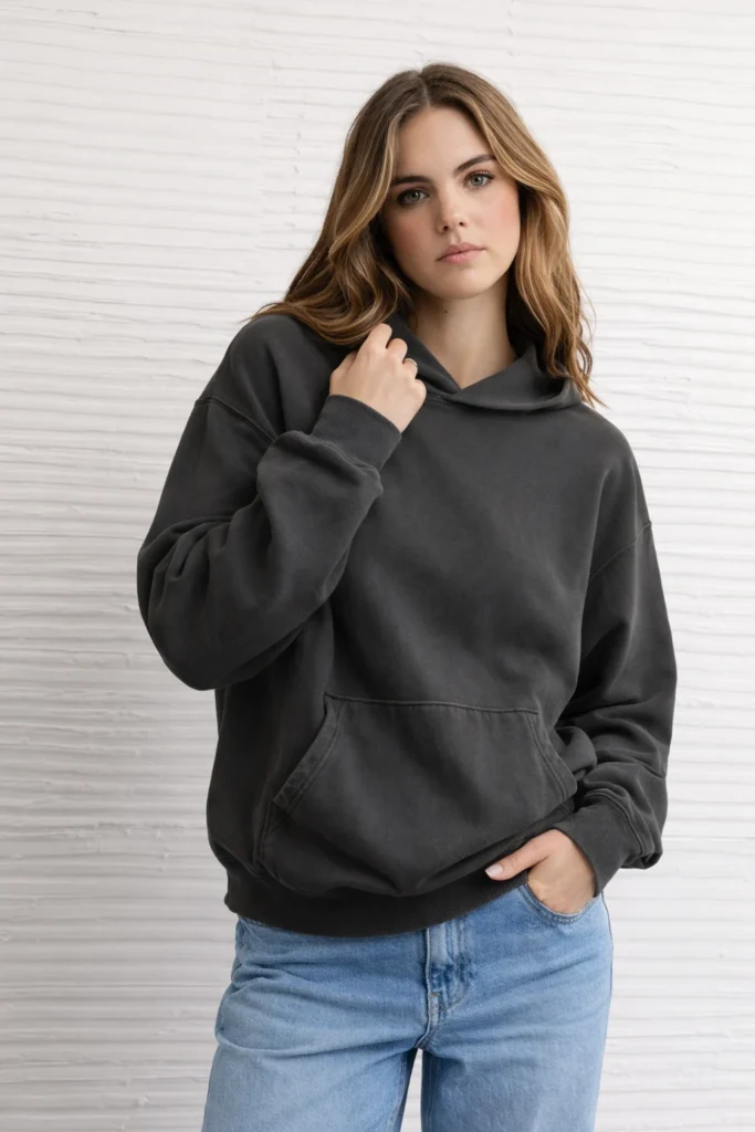 A clean lifestyle image showcasing a charcoal pullover hoodie with a subtle washed finish and relaxed silhouette. Designed with a spacious hood, ribbed cuffs and hem, and a classic kangaroo pocket, this hoodie delivers a casual, lived-in aesthetic ideal for modern streetwear and everyday wear. The neutral dark tone makes it perfect for private label customization, minimalist branding, and versatile unisex collections targeting contemporary casual markets.